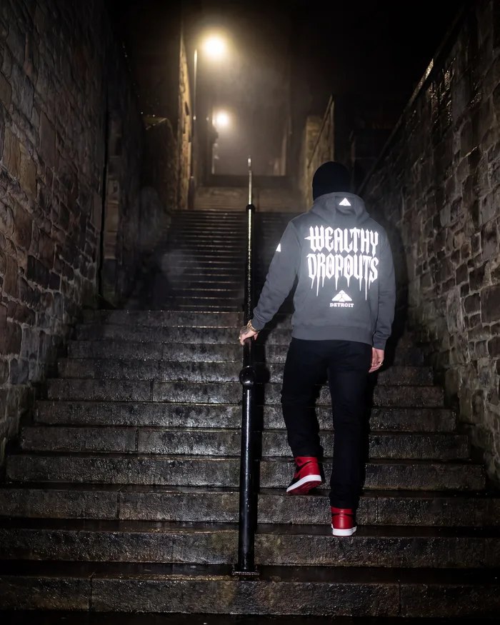 Charcoal heather, worn from behind: climbing a long wet stone stairway at night in mist