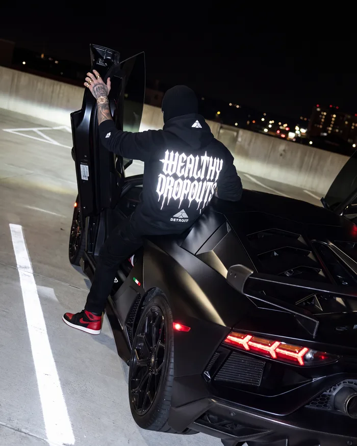Worn, from behind: stepping into a black car on a parking deck at night, the back print lit white by the flash